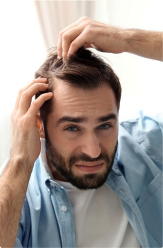 Man looking at his scalp and touching hair while looking at the mirror needing hair restoration in Tucson, AZ