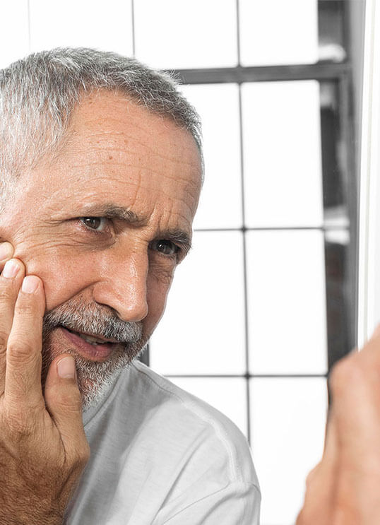 Man looking at Mirror after facial rejuvenation from Beauty & Health by Liz in Tucson