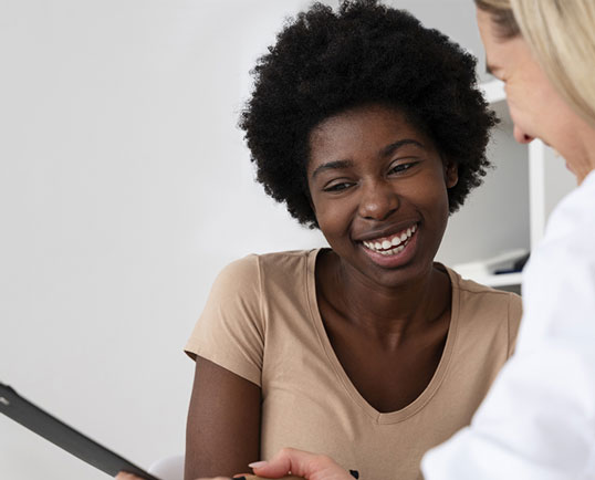 Woman smiling with her aesthetician at Beauty & Health by Liz