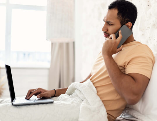 Man using a phone and a laptop