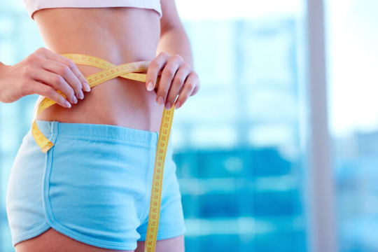 Woman measuring waist with tape measure